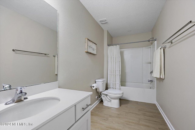 full bathroom featuring shower / bath combination with curtain, vanity, a textured ceiling, hardwood / wood-style floors, and toilet