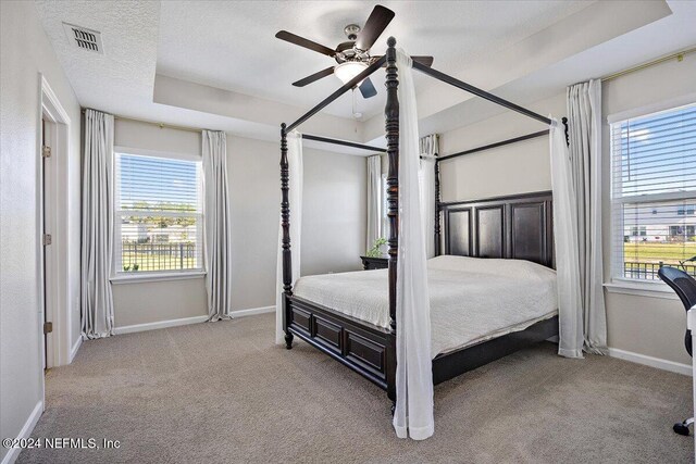 bedroom featuring ceiling fan, light colored carpet, and multiple windows