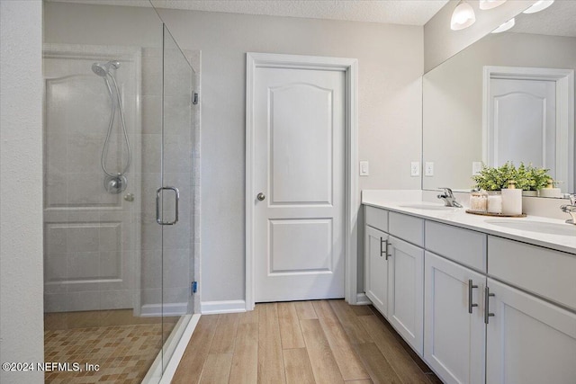 bathroom with walk in shower, vanity, a textured ceiling, and hardwood / wood-style flooring