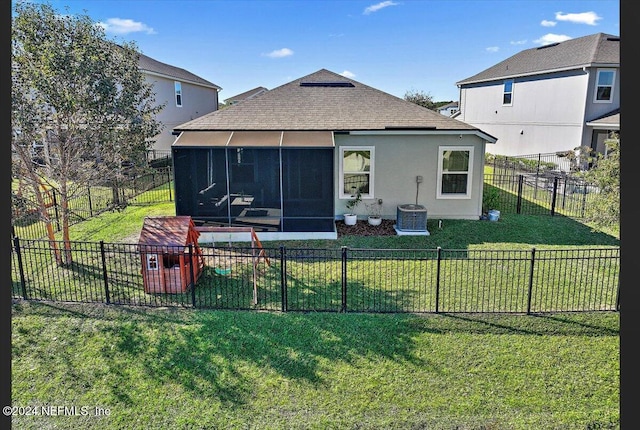 rear view of house featuring a lawn, cooling unit, and a sunroom