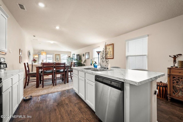 kitchen featuring dark wood-type flooring, a kitchen island with sink, vaulted ceiling, stainless steel dishwasher, and white cabinetry