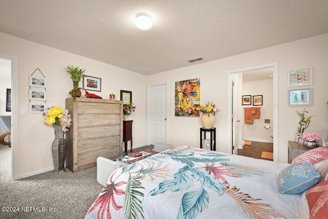 carpeted bedroom with ensuite bathroom and a textured ceiling