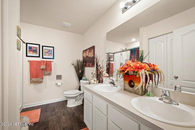 bathroom with hardwood / wood-style floors, vanity, toilet, walk in shower, and a textured ceiling