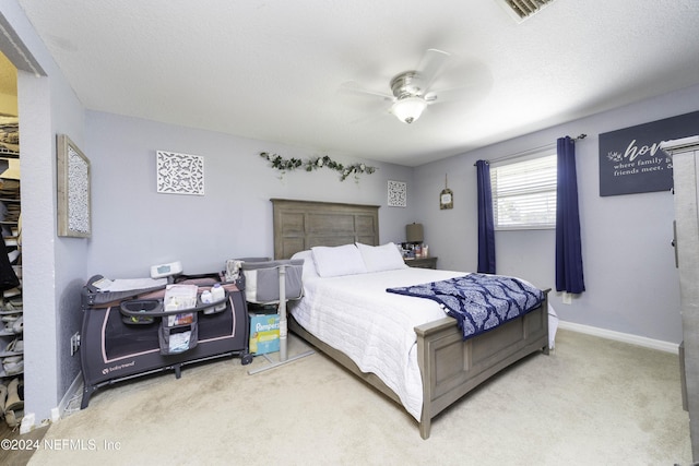 carpeted bedroom featuring ceiling fan and a textured ceiling