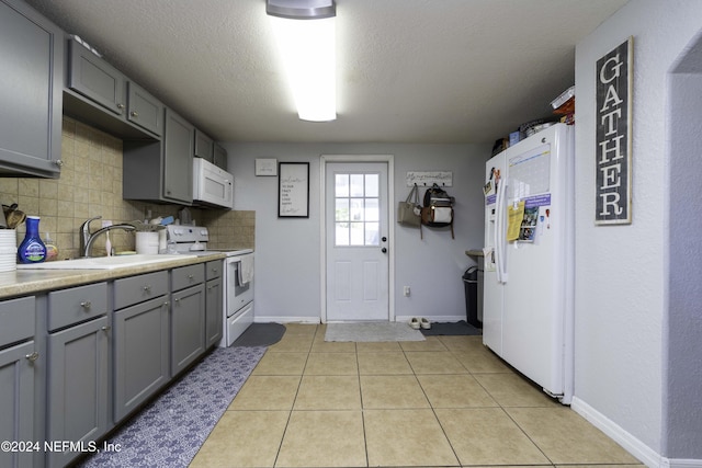 kitchen featuring gray cabinets, white appliances, backsplash, and light tile patterned floors