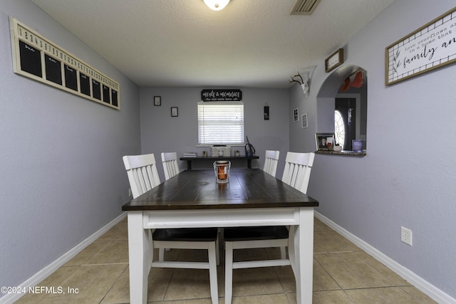 tiled dining room featuring a textured ceiling