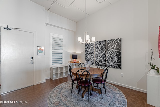 dining area featuring a notable chandelier, a towering ceiling, and dark wood-type flooring