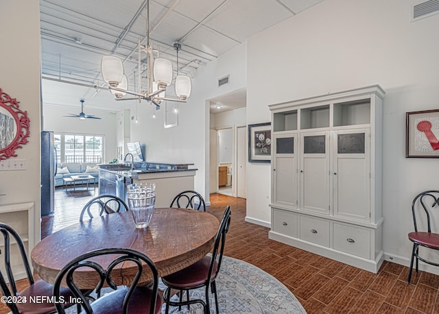 dining room with ceiling fan with notable chandelier, dark hardwood / wood-style floors, a towering ceiling, and sink