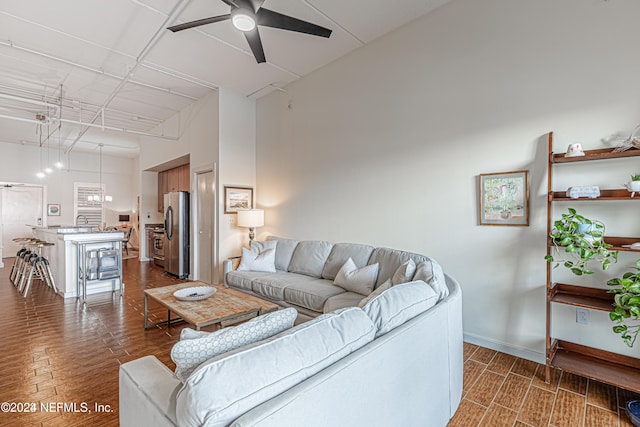 living room with ceiling fan, dark hardwood / wood-style floors, a towering ceiling, and sink