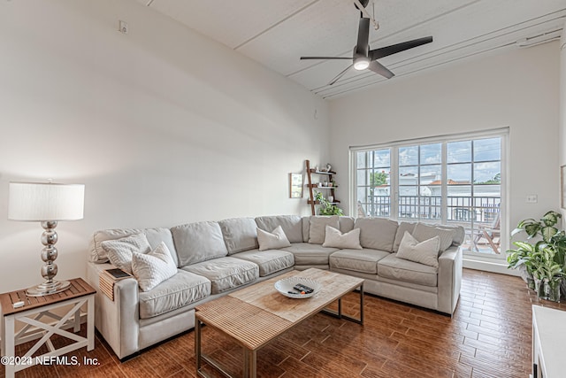 living room with ceiling fan, dark hardwood / wood-style flooring, and a high ceiling