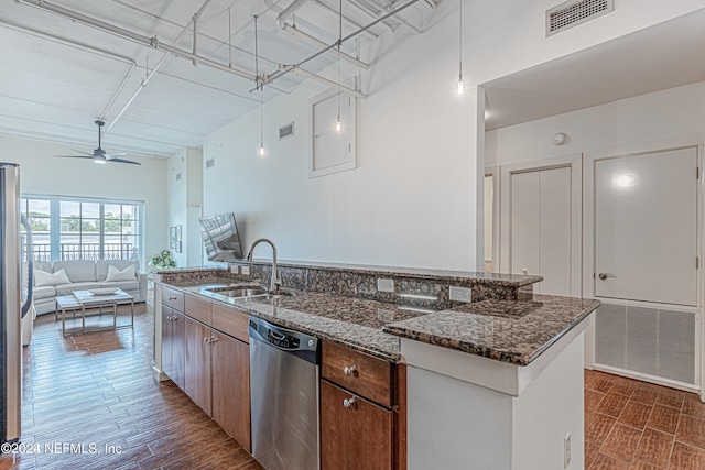 kitchen with dishwasher, dark stone countertops, sink, and a kitchen island with sink