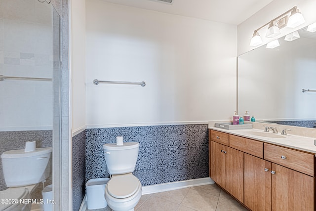 bathroom featuring tile patterned flooring, vanity, toilet, and tile walls