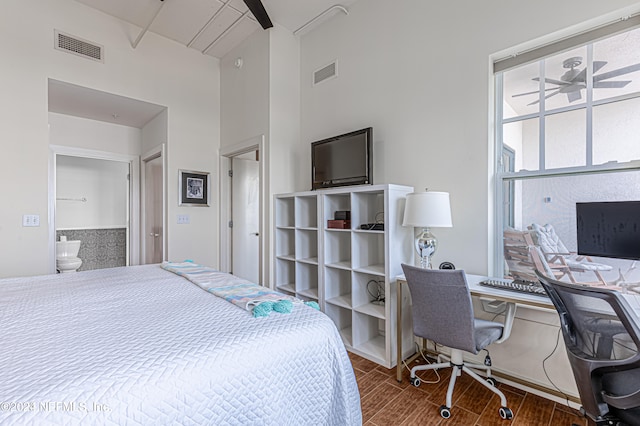 bedroom featuring ensuite bathroom, a towering ceiling, and dark wood-type flooring