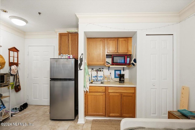 kitchen featuring light tile patterned floors, ornamental molding, and stainless steel refrigerator