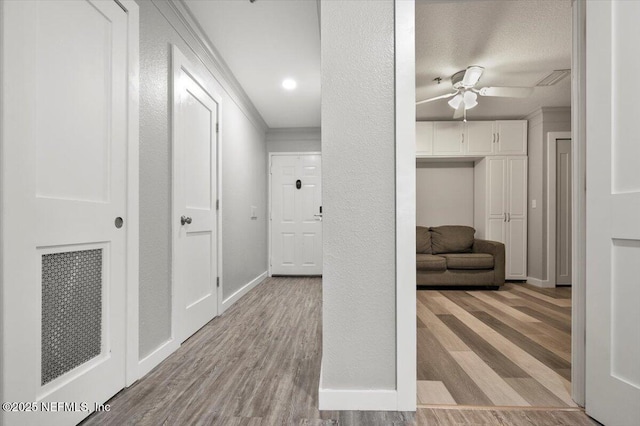 corridor featuring ornamental molding and light hardwood / wood-style floors