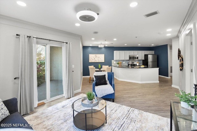 living room featuring ornamental molding and light hardwood / wood-style floors