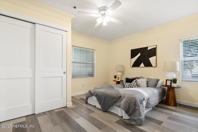 bedroom with ornamental molding, ceiling fan, light hardwood / wood-style floors, and a closet