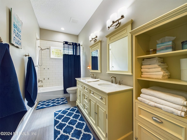 full bathroom with shower / tub combo, vanity, a textured ceiling, wood-type flooring, and toilet