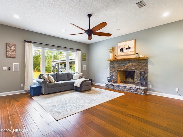 unfurnished living room with a textured ceiling, a fireplace, ceiling fan, and dark wood-type flooring