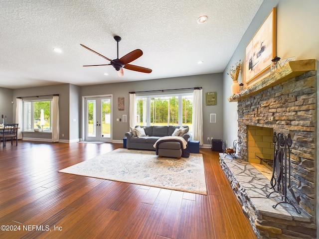 living room with a fireplace, a healthy amount of sunlight, a textured ceiling, and wood-type flooring