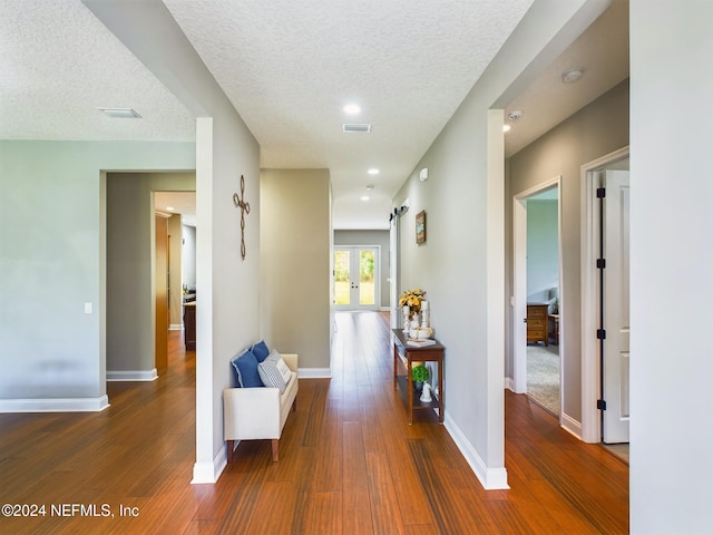 hall featuring french doors, dark hardwood / wood-style flooring, and a textured ceiling