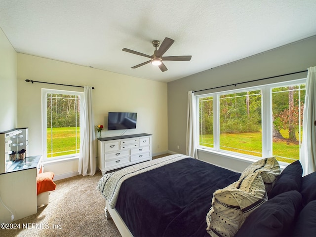 bedroom featuring ceiling fan, light colored carpet, and a textured ceiling