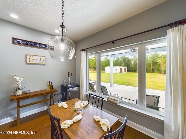 dining area with a textured ceiling and dark wood-type flooring