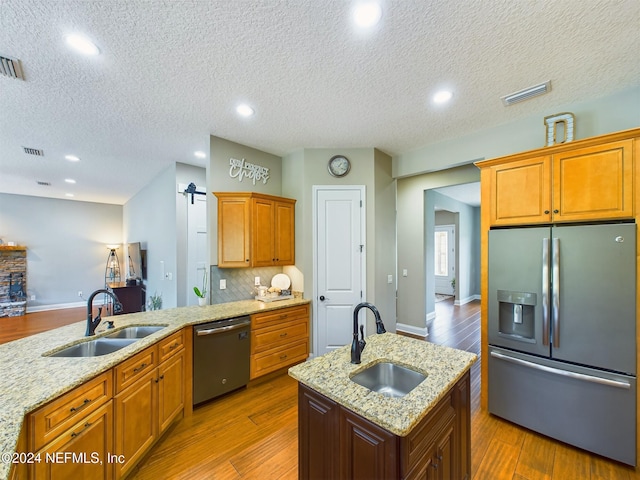 kitchen featuring hardwood / wood-style floors, sink, appliances with stainless steel finishes, and a textured ceiling