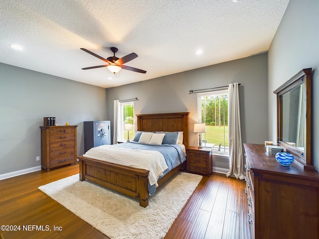 bedroom featuring multiple windows, ceiling fan, dark hardwood / wood-style flooring, and a textured ceiling