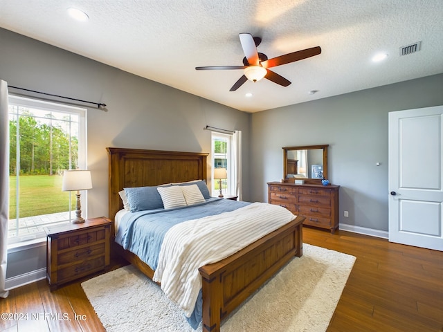 bedroom with ceiling fan, dark wood-type flooring, and a textured ceiling