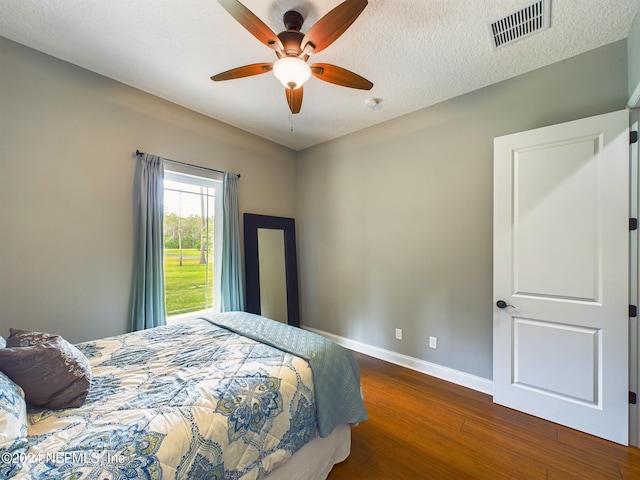 bedroom with ceiling fan, dark hardwood / wood-style flooring, and a textured ceiling