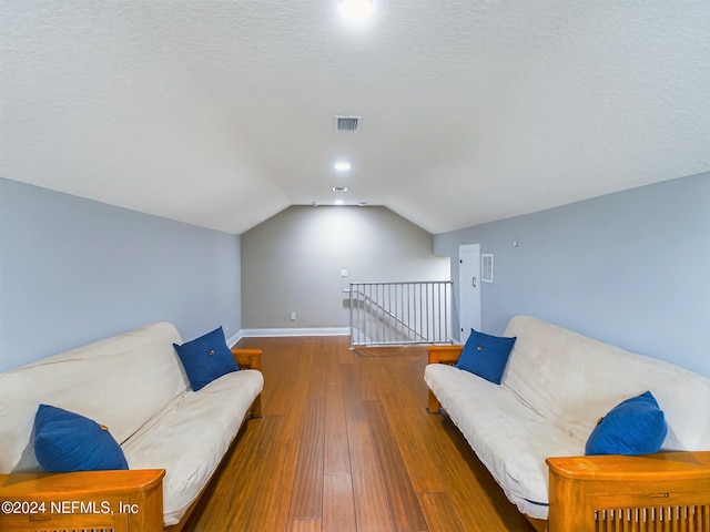 living area with a textured ceiling, lofted ceiling, and dark hardwood / wood-style floors