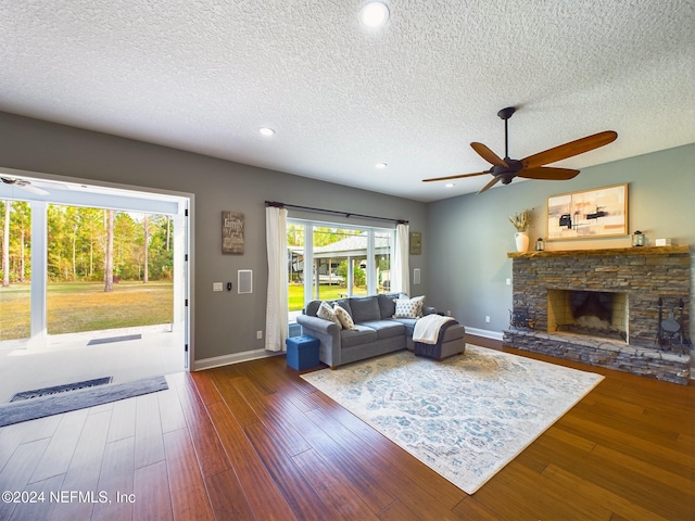 living room featuring a fireplace, a textured ceiling, dark hardwood / wood-style flooring, and ceiling fan