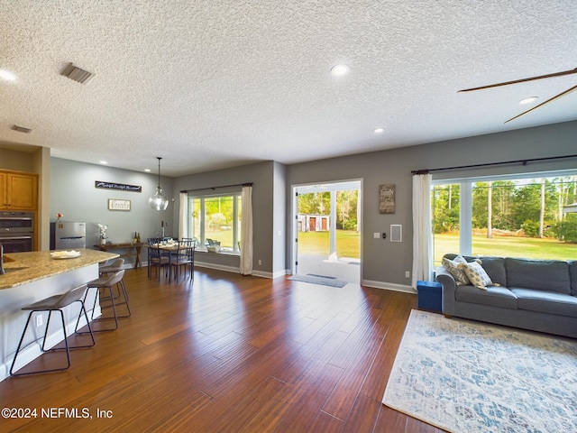 living room with a textured ceiling and dark wood-type flooring