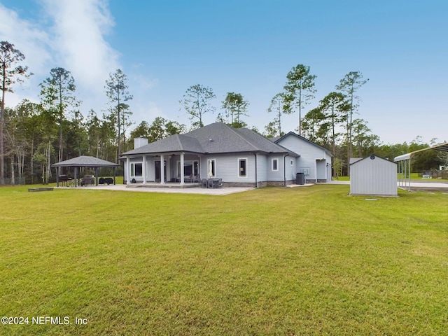 back of property with a gazebo, a patio, a storage unit, and a lawn