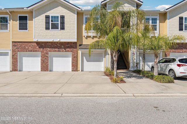 multi unit property with a garage, brick siding, and driveway