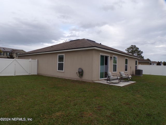 back of house featuring central air condition unit, a patio area, and a lawn