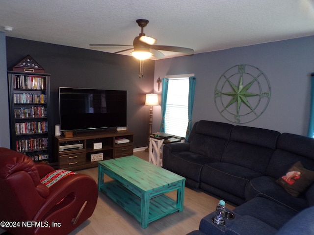 living room with ceiling fan, light hardwood / wood-style floors, and a textured ceiling