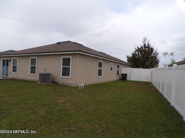 rear view of house with a lawn and central AC