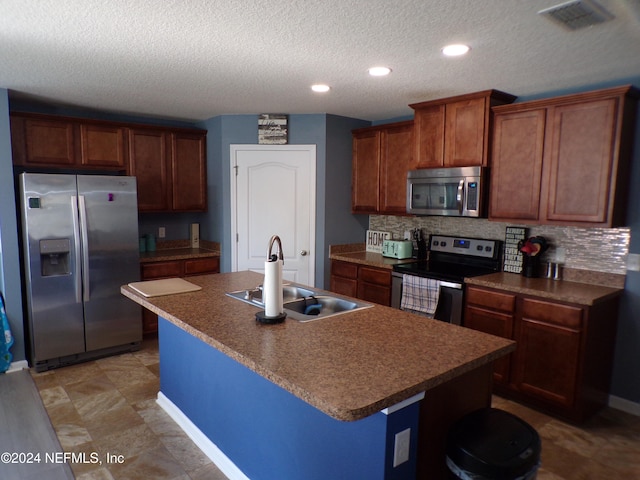 kitchen featuring appliances with stainless steel finishes, a center island with sink, tasteful backsplash, and sink