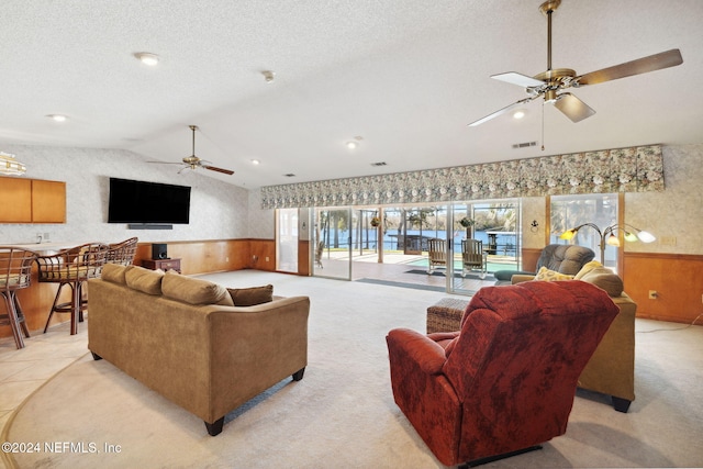 carpeted living room with a textured ceiling, vaulted ceiling, ceiling fan, and wooden walls