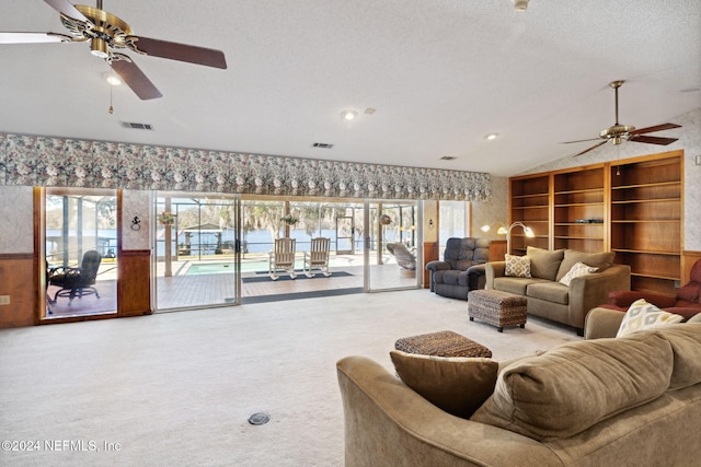 carpeted living room with a textured ceiling, ceiling fan, and vaulted ceiling