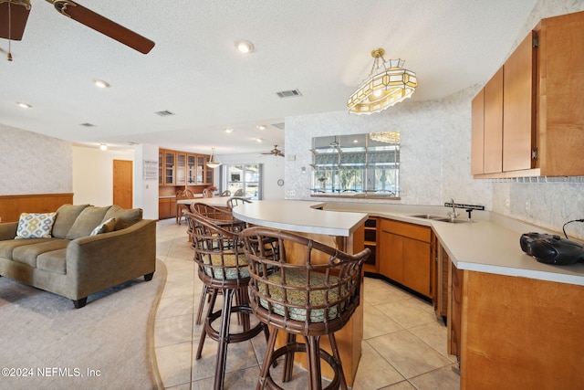 kitchen with a textured ceiling, ceiling fan, sink, and hanging light fixtures