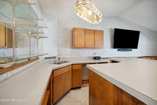 kitchen with a textured ceiling, sink, light tile patterned floors, pendant lighting, and lofted ceiling