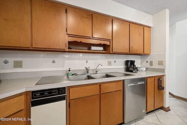 kitchen featuring sink, stainless steel dishwasher, decorative backsplash, light tile patterned floors, and a textured ceiling