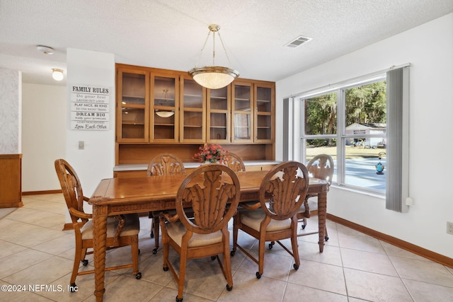 dining space featuring light tile patterned floors and a textured ceiling