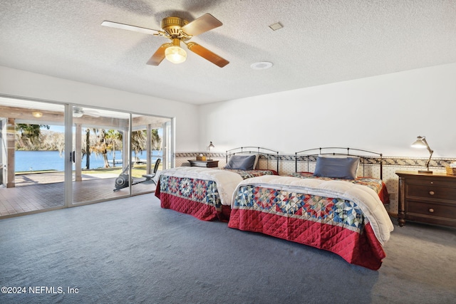 bedroom featuring carpet flooring, a textured ceiling, access to outside, ceiling fan, and a water view