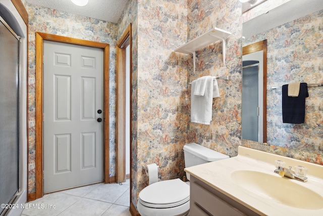 bathroom with tile patterned flooring, a textured ceiling, toilet, vanity, and a shower with shower door