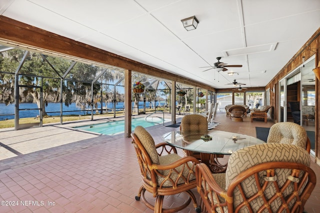 sunroom / solarium with a water view, a pool, and ceiling fan