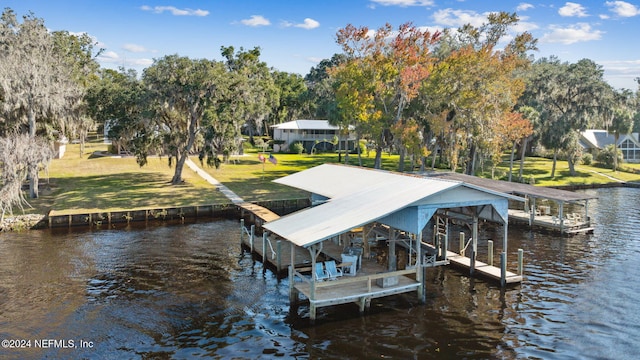 view of dock with a yard and a water view